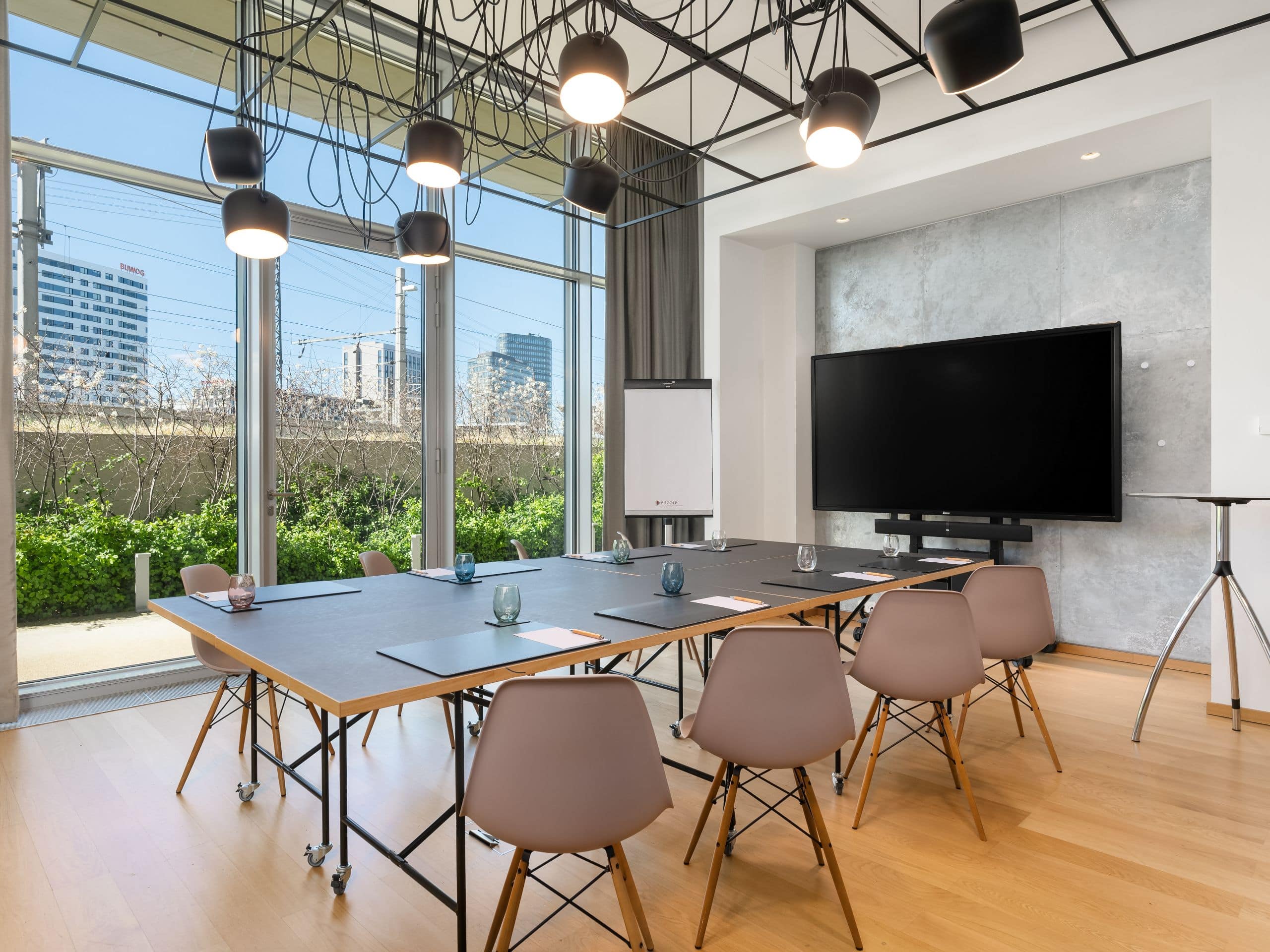 A meeting room with a modern setup and a view outside through large windows