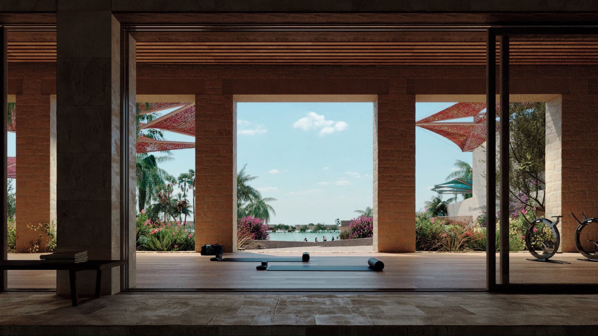 Open-air fitness area with exercise mats, dumbbells, and a bicycle, overlooking a pool and greenery through large wooden beams – a top choice for a gym in the Red Sea