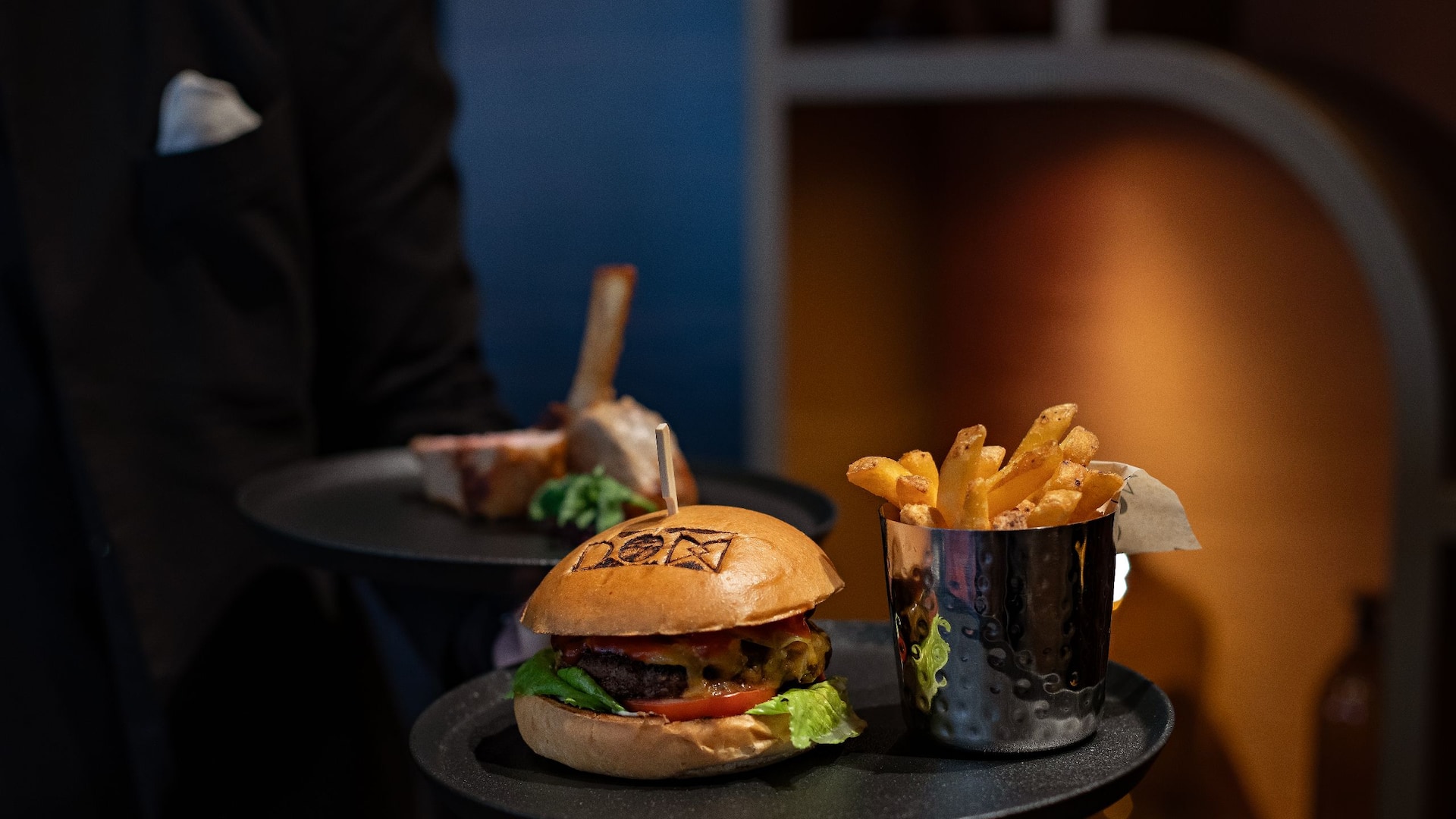 DOX Restaurant at the Hyatt Regency Dusseldorf, the waiter brings two dishes to the table, one burger and fries and veal loin