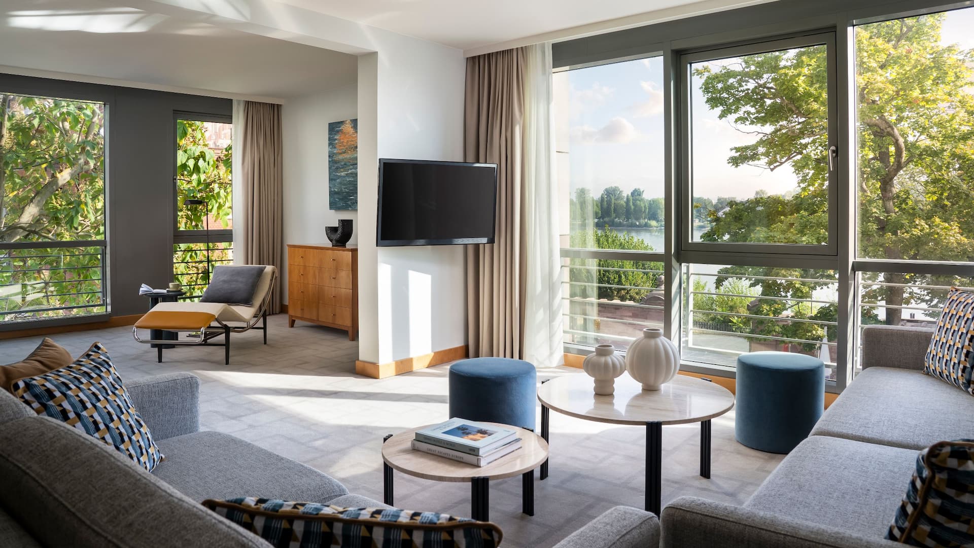 Stylish living room in Hyatt Regency Mainz apartment with views of trees and the Rhine river