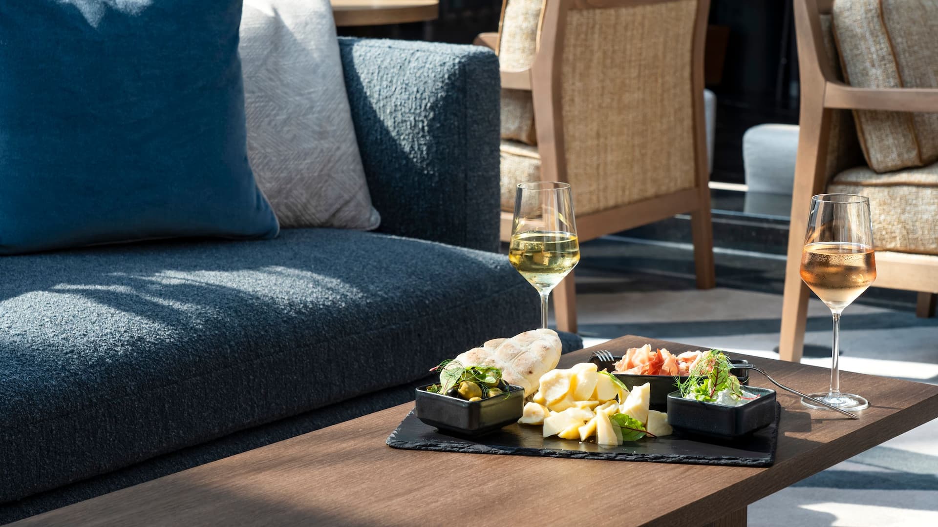 Comfortable sofa and table with wine and tapas plate in the inviting ambience of the M Lounge at Hyatt Regency Mainz