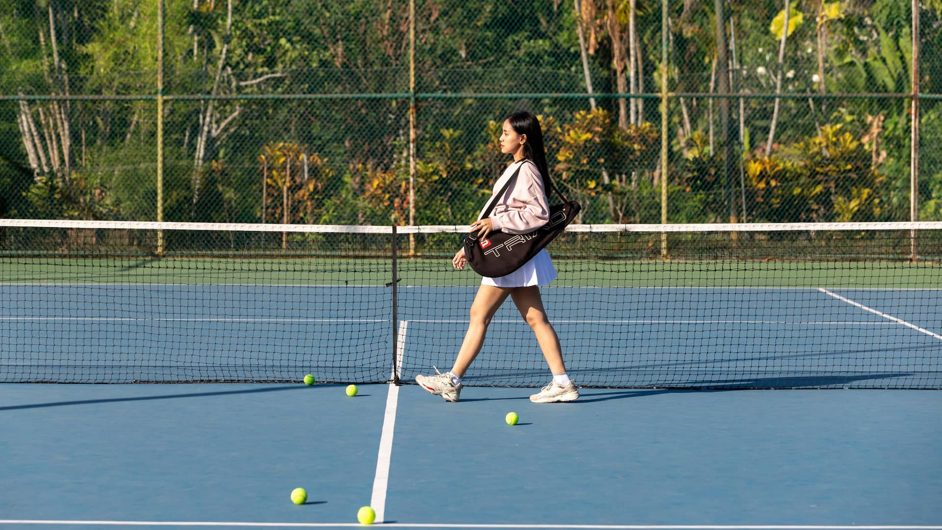 Hyatt Regency Yogyakarta A Woman Walking On A Tennis Court