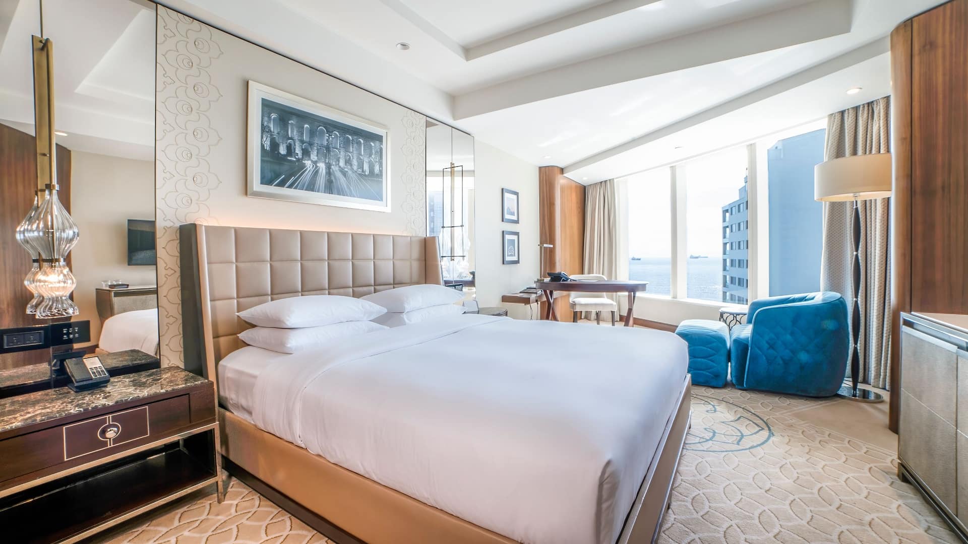 3 de 7 1 King Bed Deluxe at Hyatt Regency Istanbul Ataköy with a tufted beige headboard, modern lighting, and wide windows offering sea views.