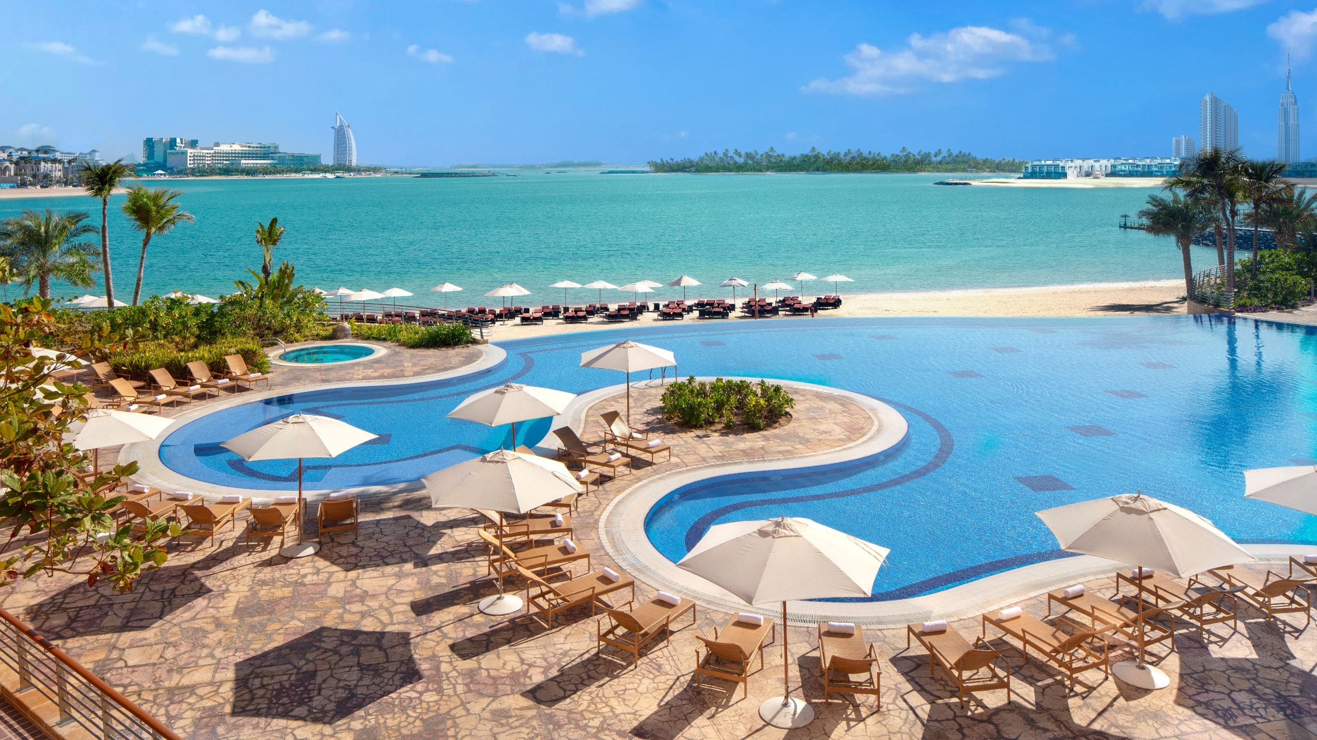 An outdoor infinity pool with access to private beach at Andaz Dubai The Palm.