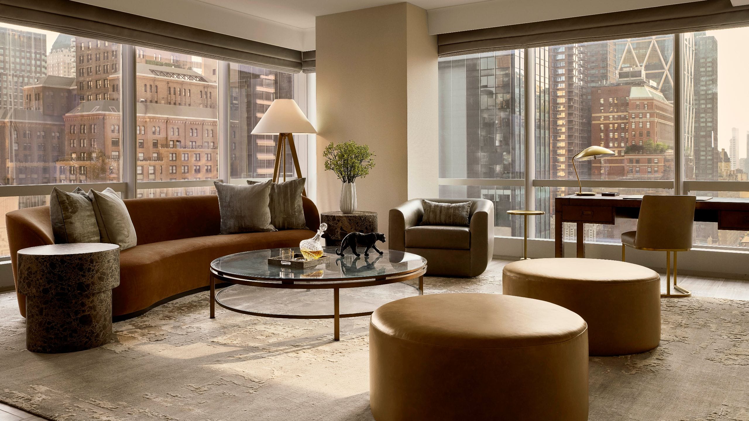 Living area in a hotel suite with a sofa, writing desk, a side chair and a bench
