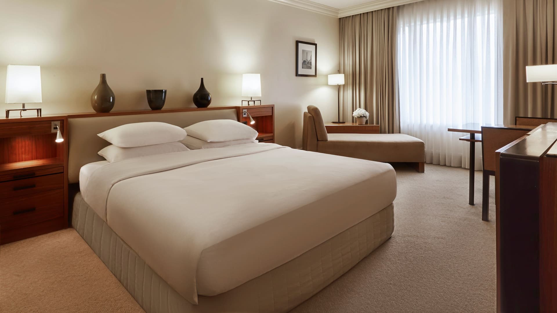1 King Bed standard room at the Luxury Istanbul hotel, Grand Hyatt Istanbul, showcasing a king-size bed with elegant vases on the headboard, a comfortable armchair, a spacious work area, and a stunning city view.