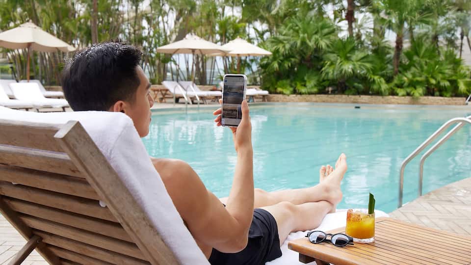 Man looking at phone by the pool
