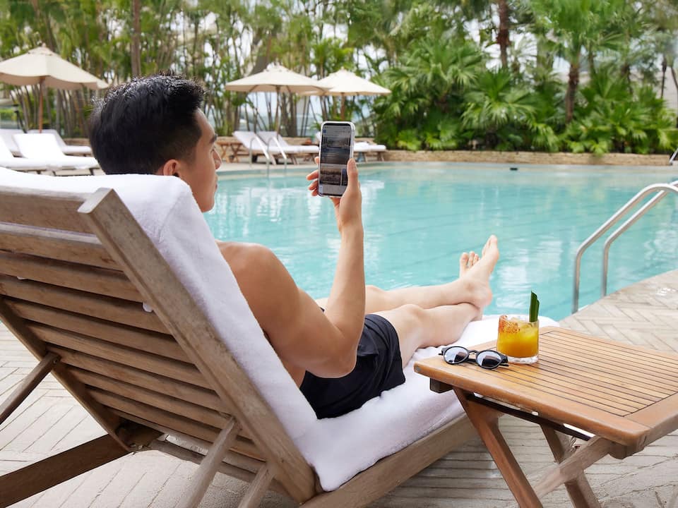 Man looking at phone by the pool